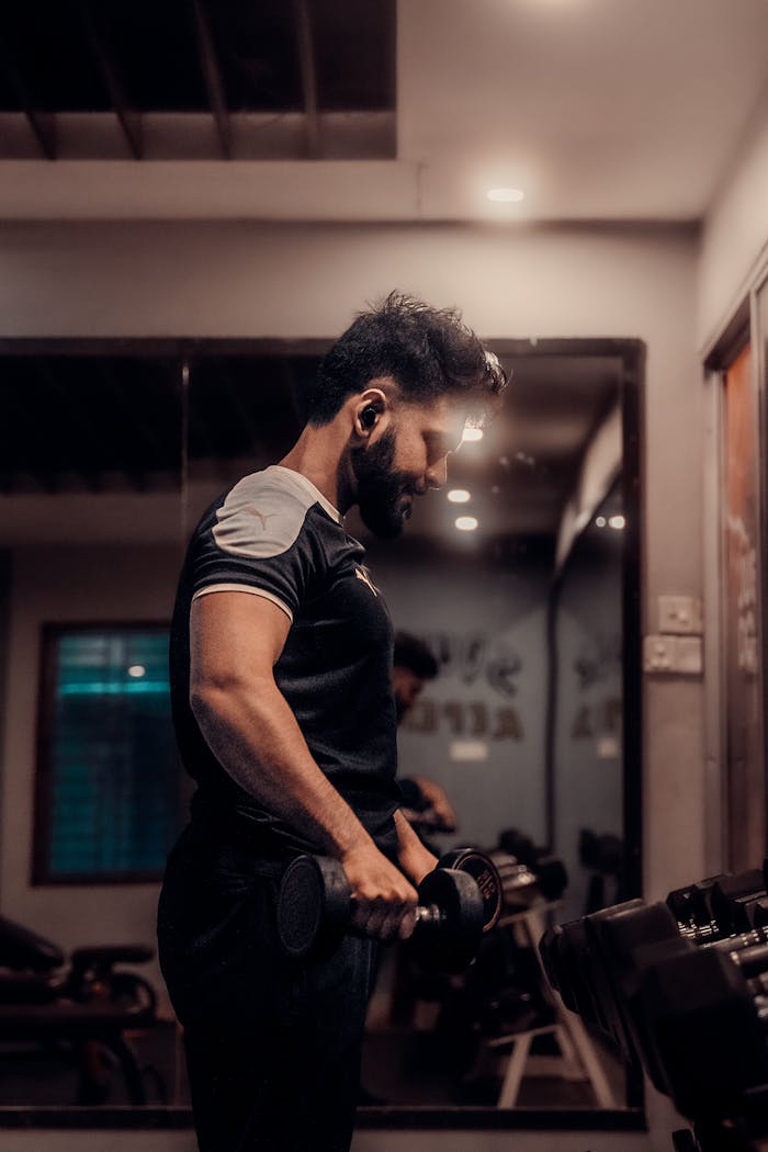 Focused man lifting dumbbells in a gym in Comilla, Bangladesh, embodying personal fitness goals.